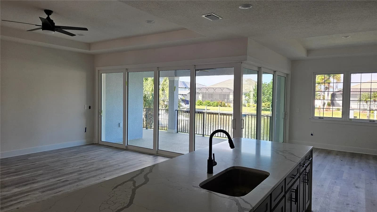 A quartz kitchen island looking through wide sliding doors to the lanai and canal