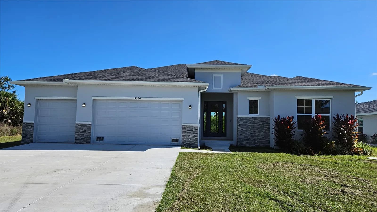 Front elevation of a completed Coastal Pointe home with a three-car garage and mature landscaping